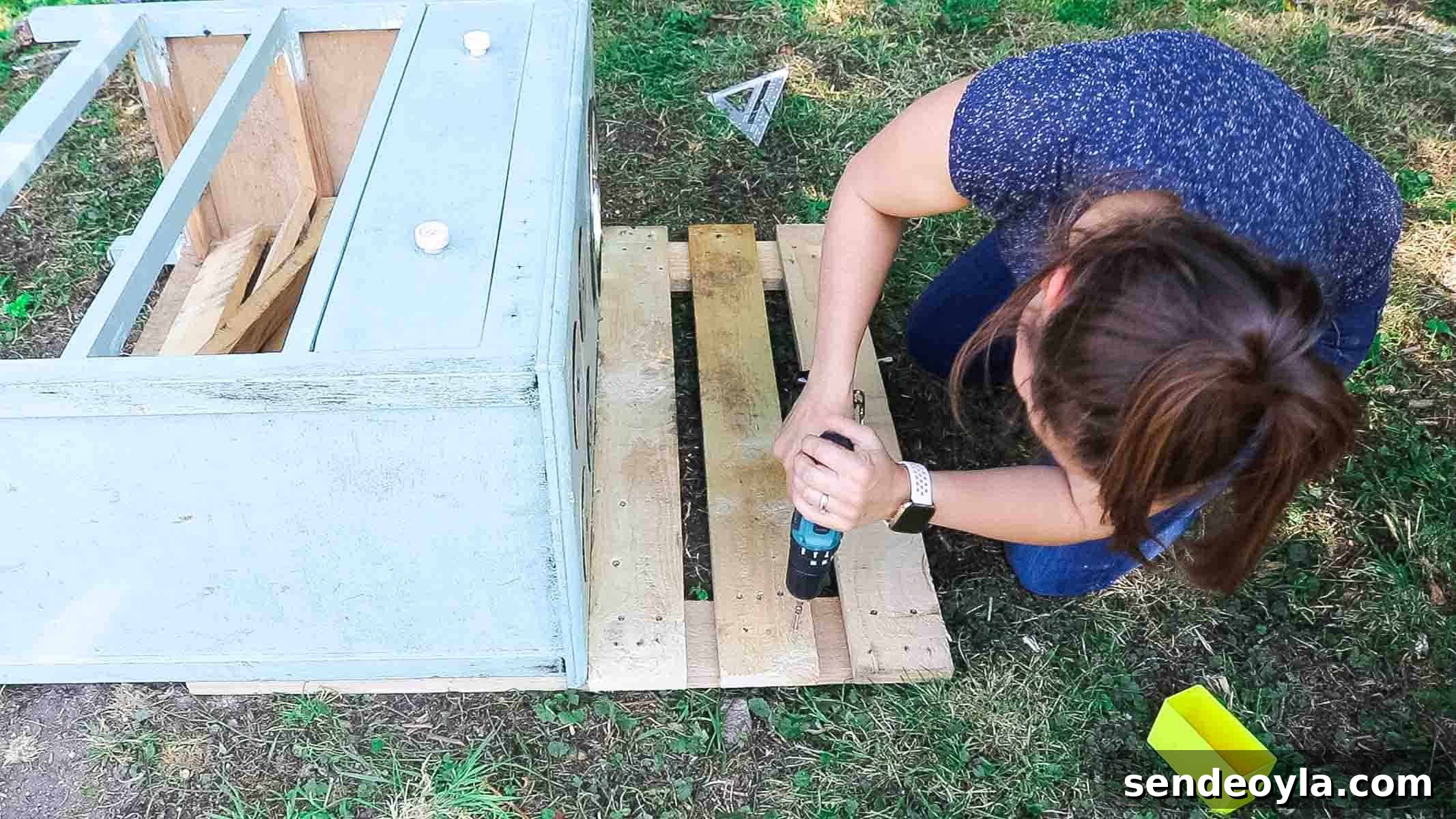 Woman making mud kitchen from pallets as a backing on some old drawers