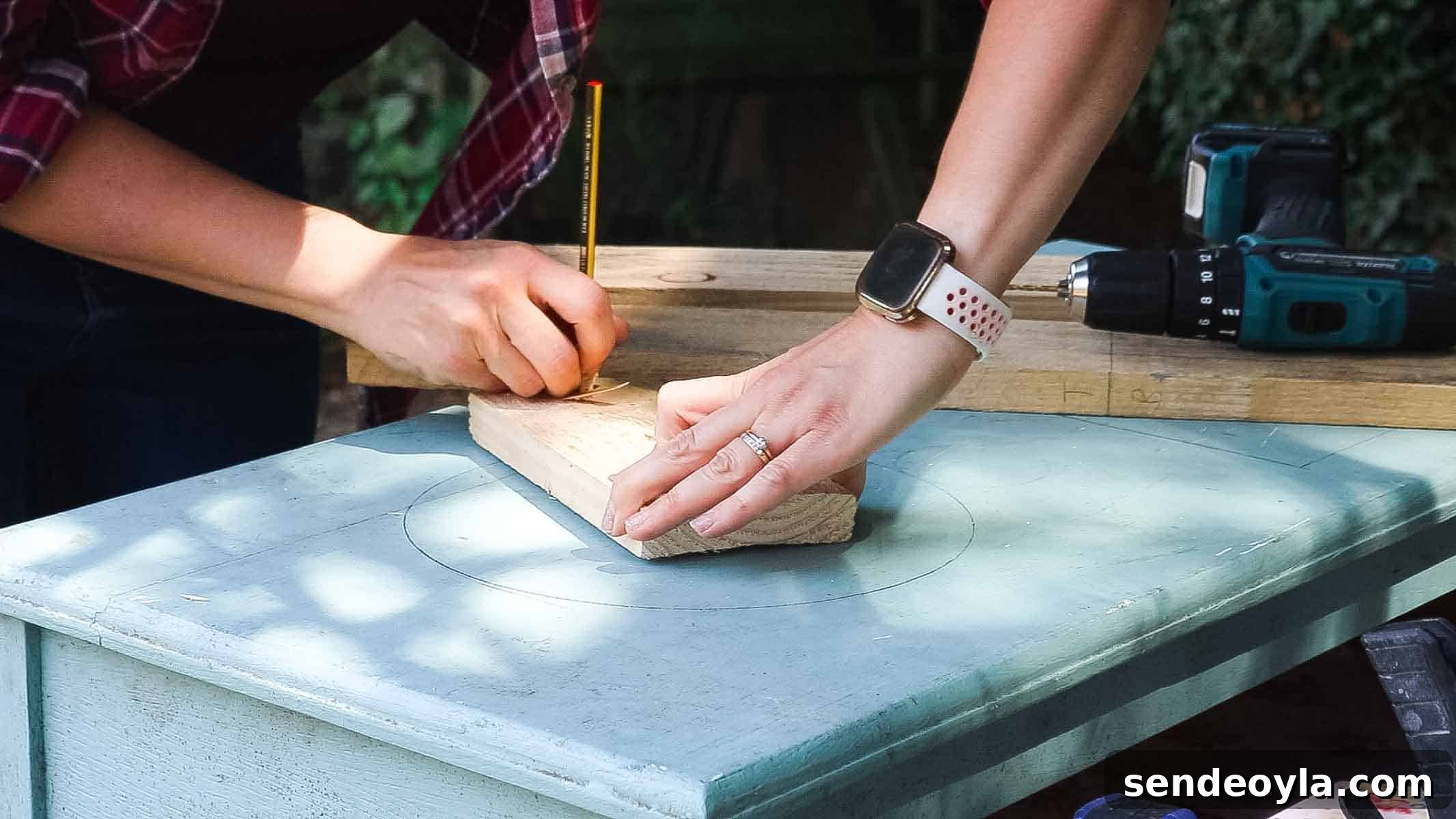 Female carpenter working on DIY kitchen crafts by drawing a perfect circle on top of an old chest of drawer to cut for a washing up bowl