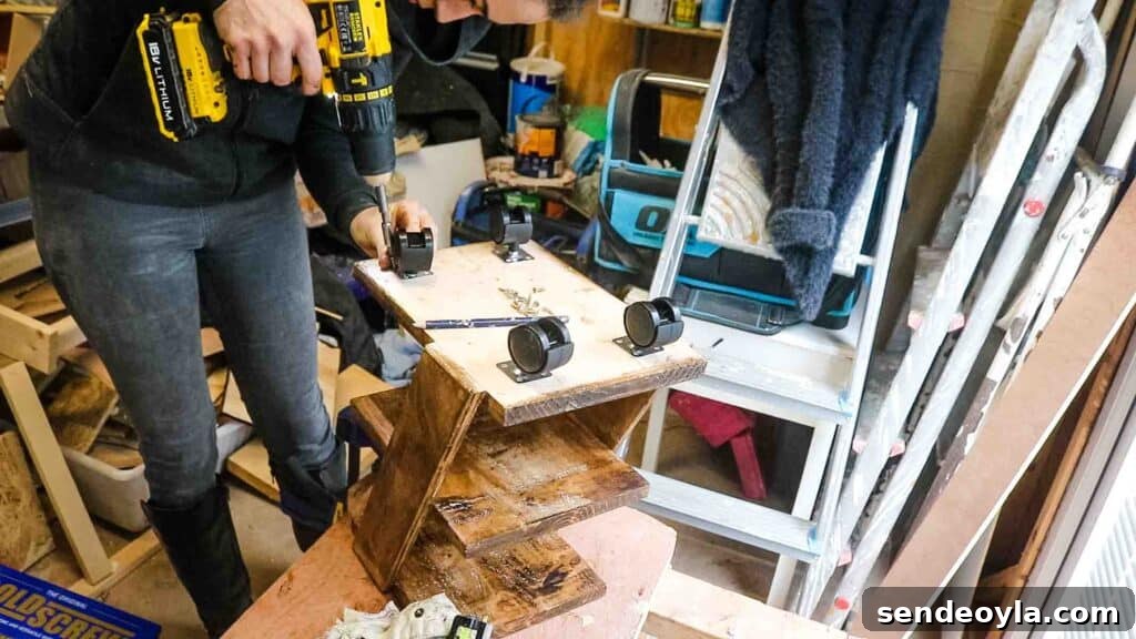 Carpenter screwing castor wheels to the bottom of a wooden 3 tier shelf to create a rolling trolley basket storage stand