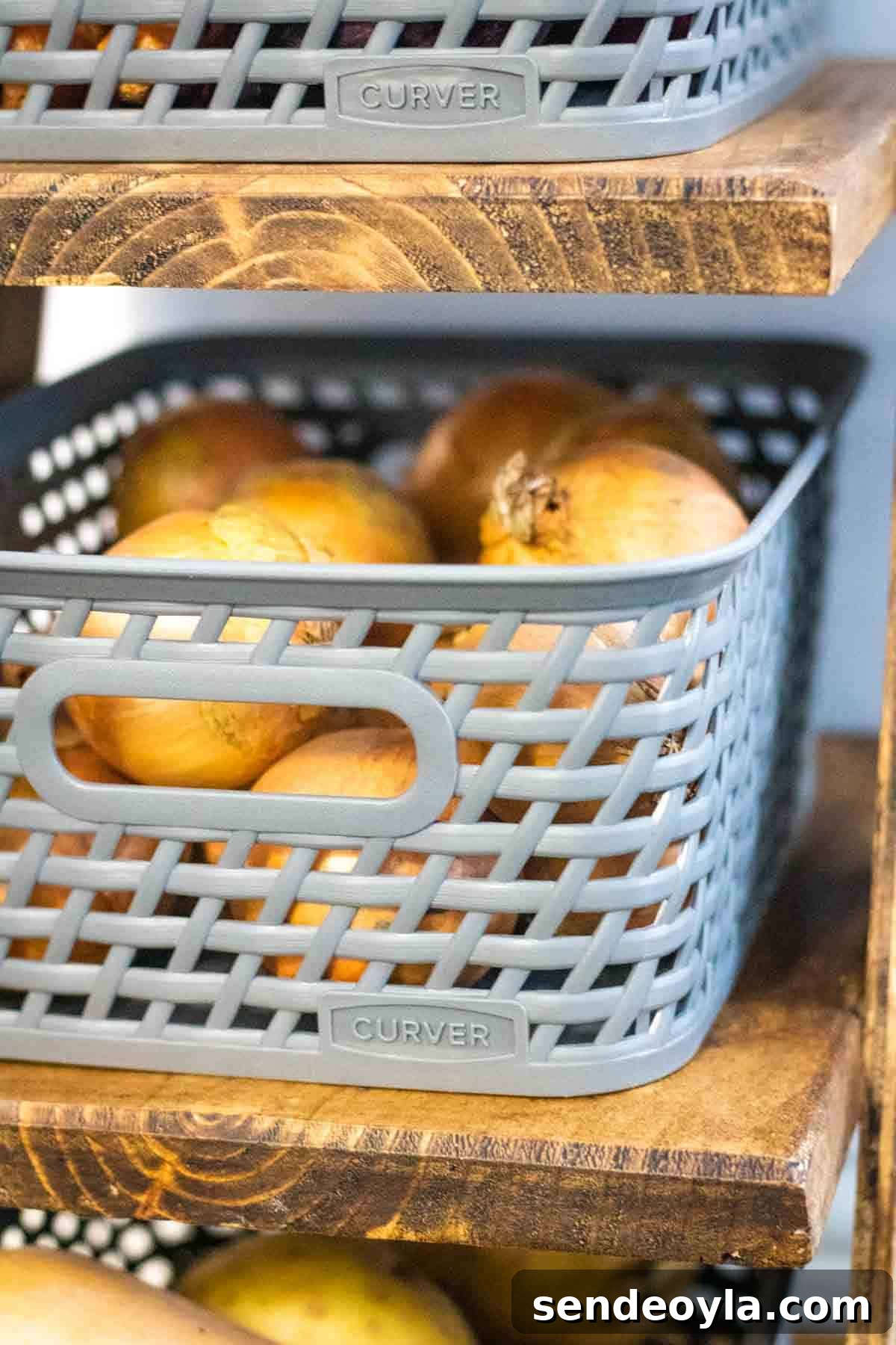 Close up of onions in grey small 4 litre Curver plastic woven baskets on a cart