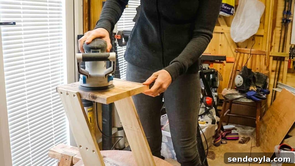 Woman using an orbital sander to sand a wooden DIY trolley
