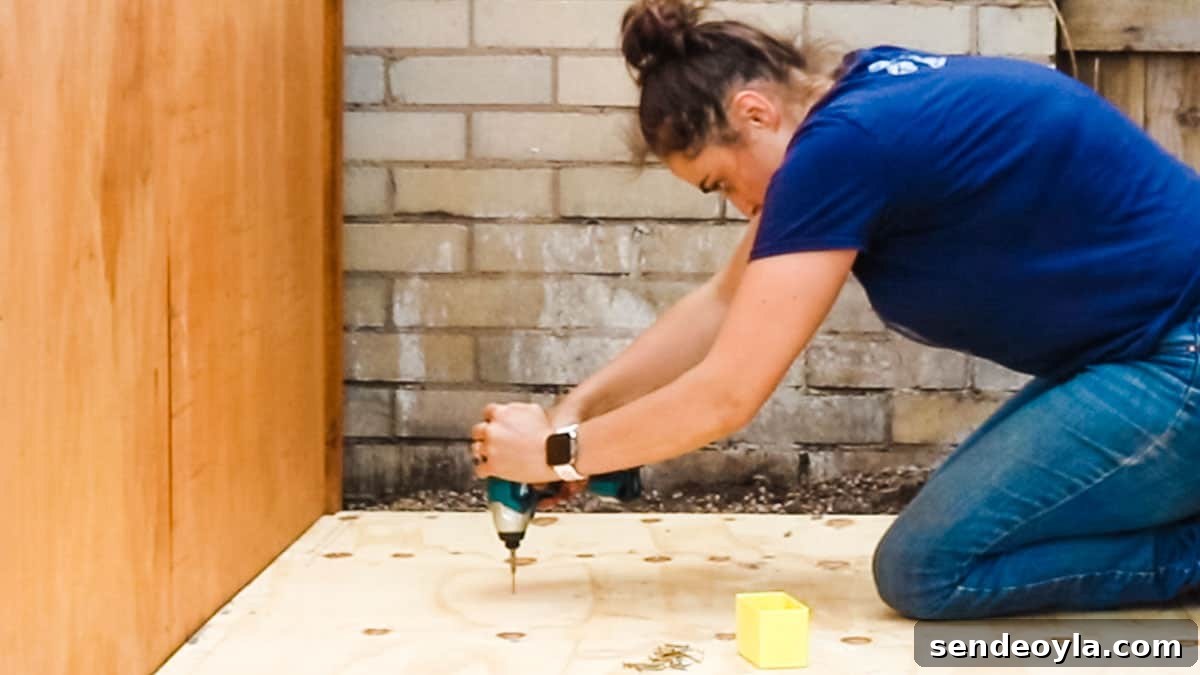 How to Build a Lean-To Shed with Free Plans 15 DIY blogger screwing plywood to shed base