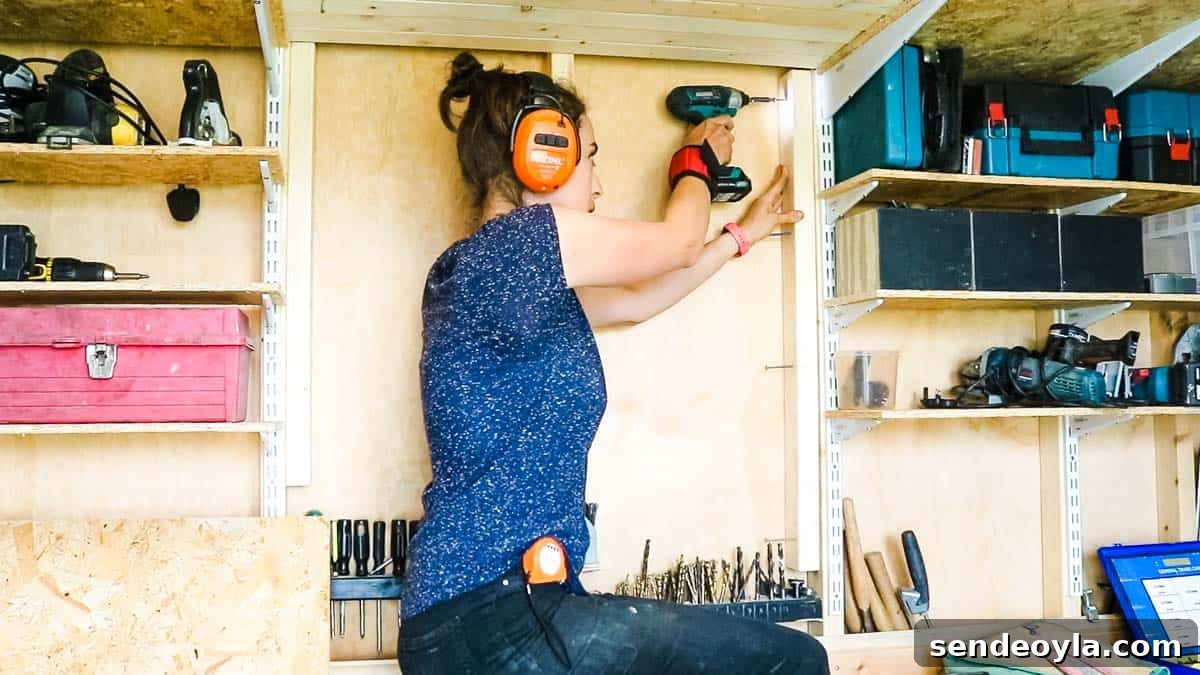 Quick DIY Wall-Mounted Tool Organizer for Garage 3 Woman screwing more spars to existing ones in a shed