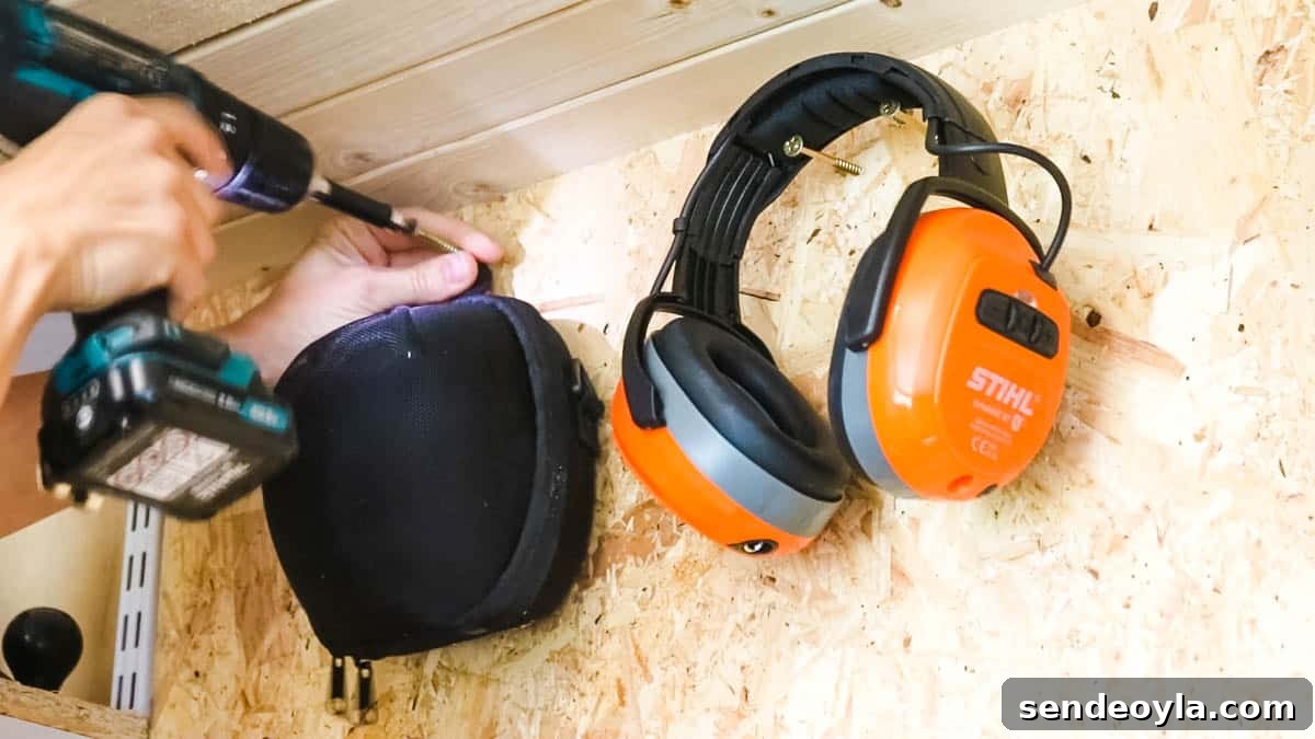 Quick DIY Wall-Mounted Tool Organizer for Garage 5 Hanging things with screws along with ear defenders to a DIY tool storage wall