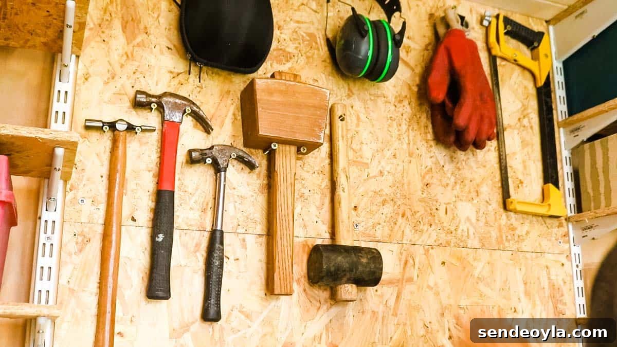 Quick DIY Wall-Mounted Tool Organizer for Garage 6 Hammers, mallets, ear defenders, gloves, hack saw hanging on a tool organizer wall