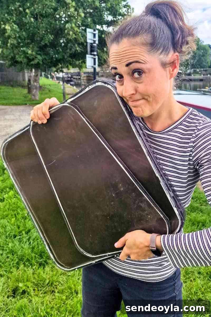 vikkie lee, the carpenter's daughter holding old plastic boat windows she found next to some bins before upcycling into a mini greenhouse