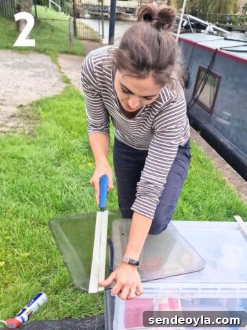woman hand sawing along marked masking tape to create a sloping side panel for angled cold frame