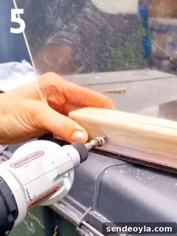 person screwing plastic to wooden frame with screws, washers and a combi drill