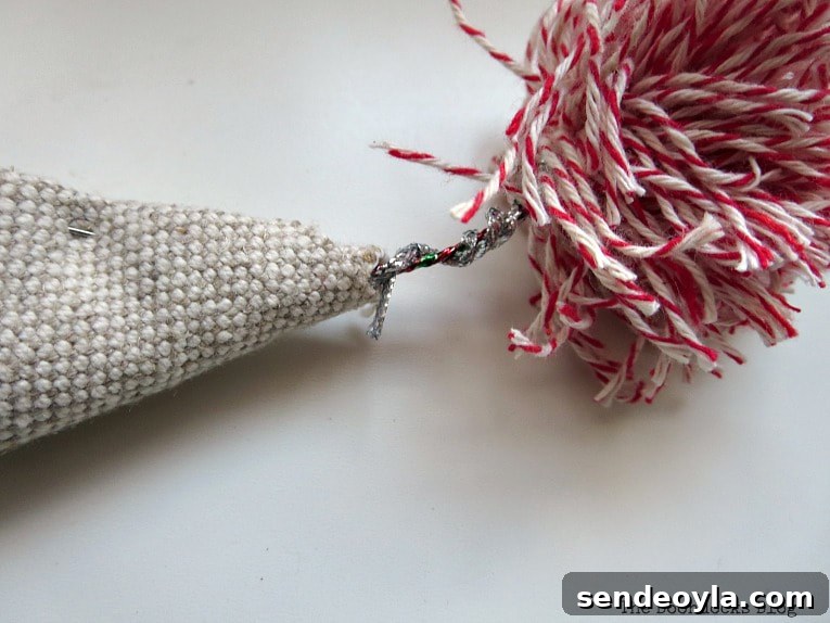 DIY Mini Christmas Tree from Dollar Store Fabric 11 Inserting the wire of the pompom into the opening of the fabric cone.