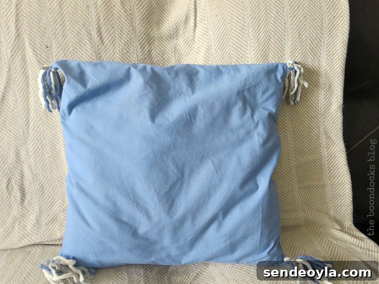 DIY Throw Pillows from Fabric Scraps: 5 Creative Ideas 12 pillow made from blue sheet with yarn tassels, How to Make Easy Pillows out of Fabric Remnants 5 ways www.theboondocksblog.com
