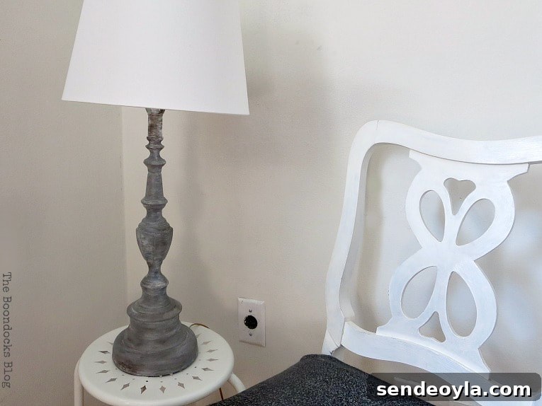 Turn a Lamp Base Into Faux Stone with Paint 10 Finished painted lamp sitting on a white table and beside a white chair.