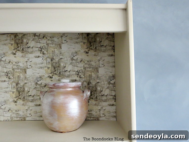 How to Paint a Cloud Accent Wall: DIY Step-by-Step Guide 19 White bookcase shelf with birch wrapping paper backing and a painted pot placed on the shelf.