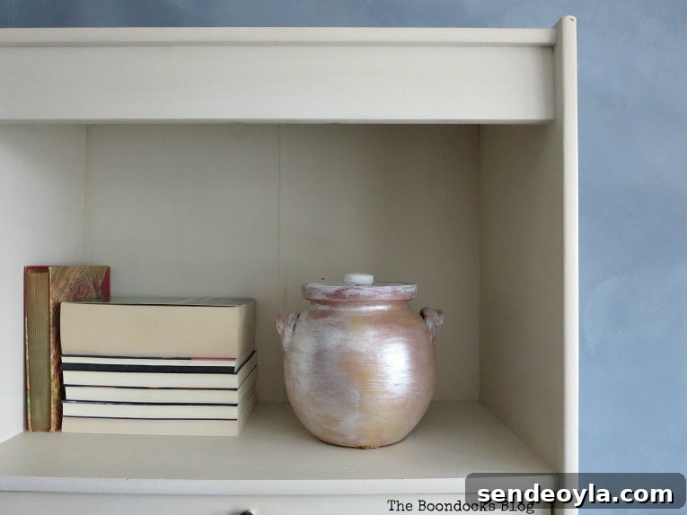 How to Paint a Cloud Accent Wall: DIY Step-by-Step Guide 20 White bookcase with off white backing and books and painted pot placed on the shelf.