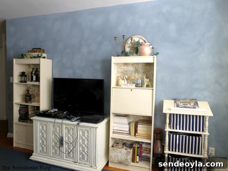 How to Paint a Cloud Accent Wall: DIY Step-by-Step Guide 21 Finished living room with furniture, TV and bookcases placed in front of the cloudy painted accent wall.