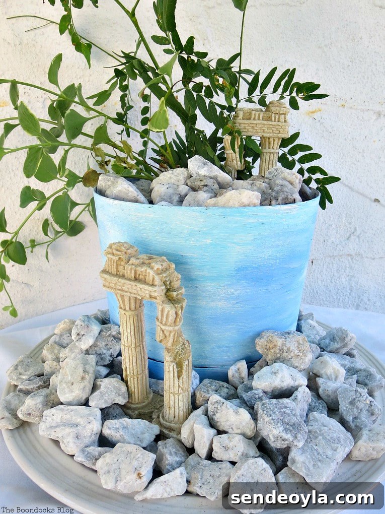 Upcycled Beach Vignette Ideas for Coastal Decor 16 planter with a beachy ancient ruin look, #beachysummerlook #ancientruins #beachyplanter #Mediterranean #plantervignette #containerplanter #pebblerockproject #vincavine #easyproject Using Pebbles to Inspire My Love of the Beach www.theboondocksblog.com