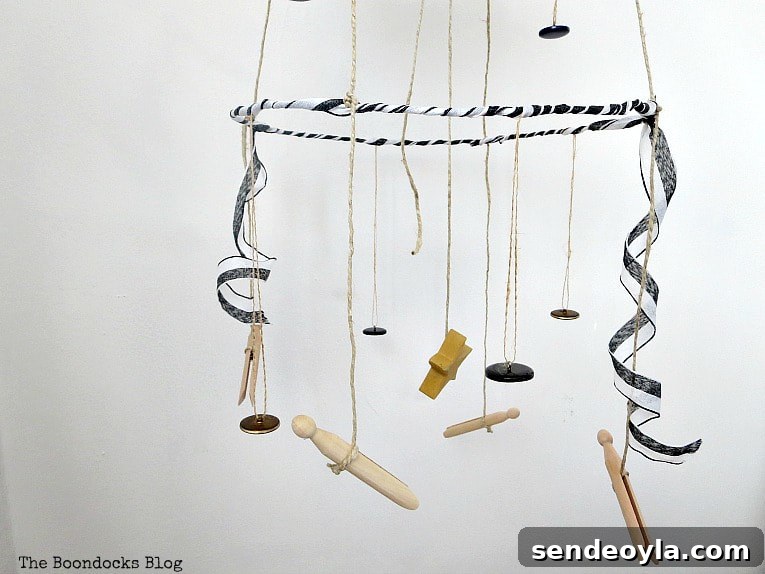 The third tier of the mobile with buttons, a star and clothespins, and ribbon.