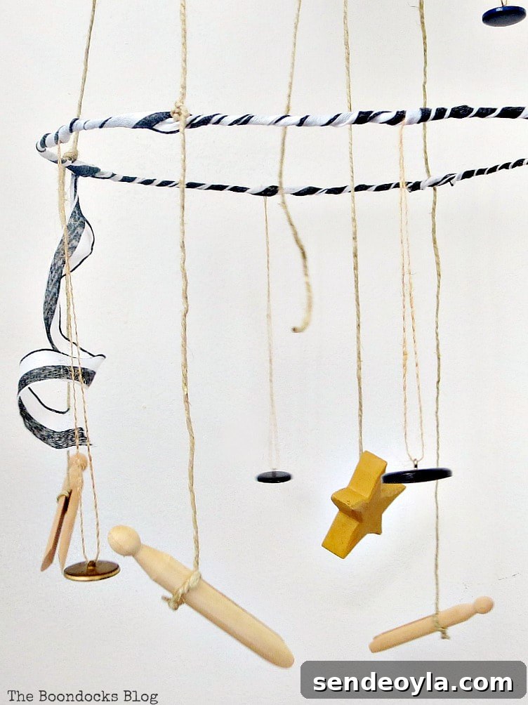 Mobile hanger with three tiers made with wire hangers, a wicker charger and twine, embellished with buttons, ribbon and a bouquet.