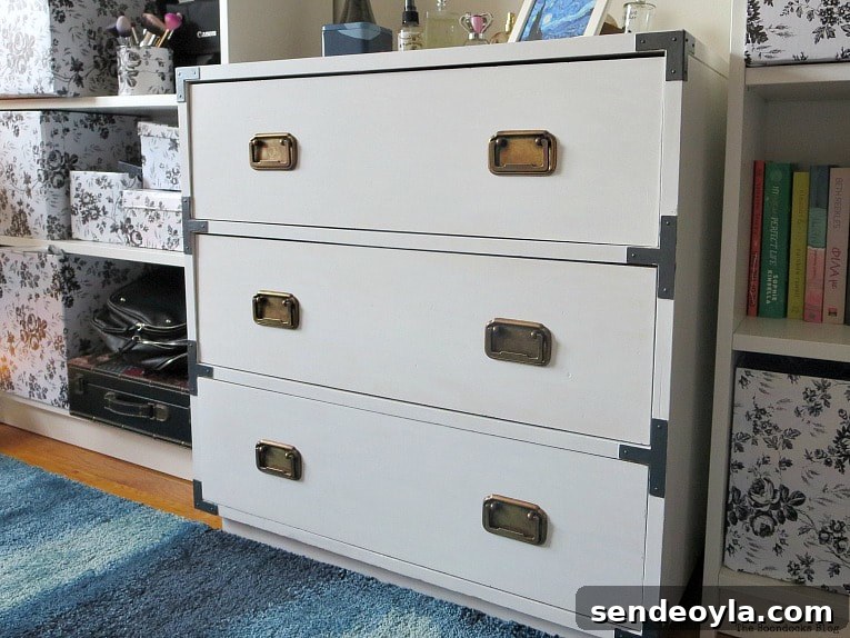 Refinish and Restore a Campaign Dresser in 7 Steps 14 Finished dresser after being painted white and updating the hardware placed in between 2 book cases.