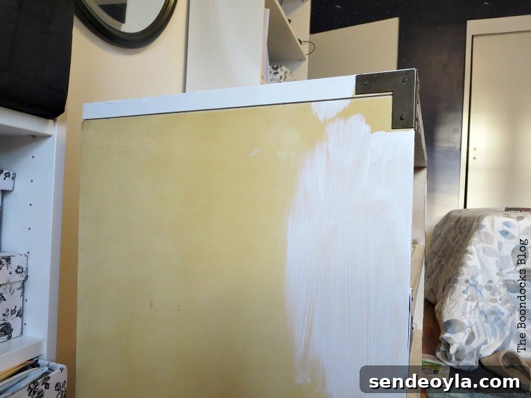 Refinish and Restore a Campaign Dresser in 7 Steps 5 Painting the side of the dresser white.