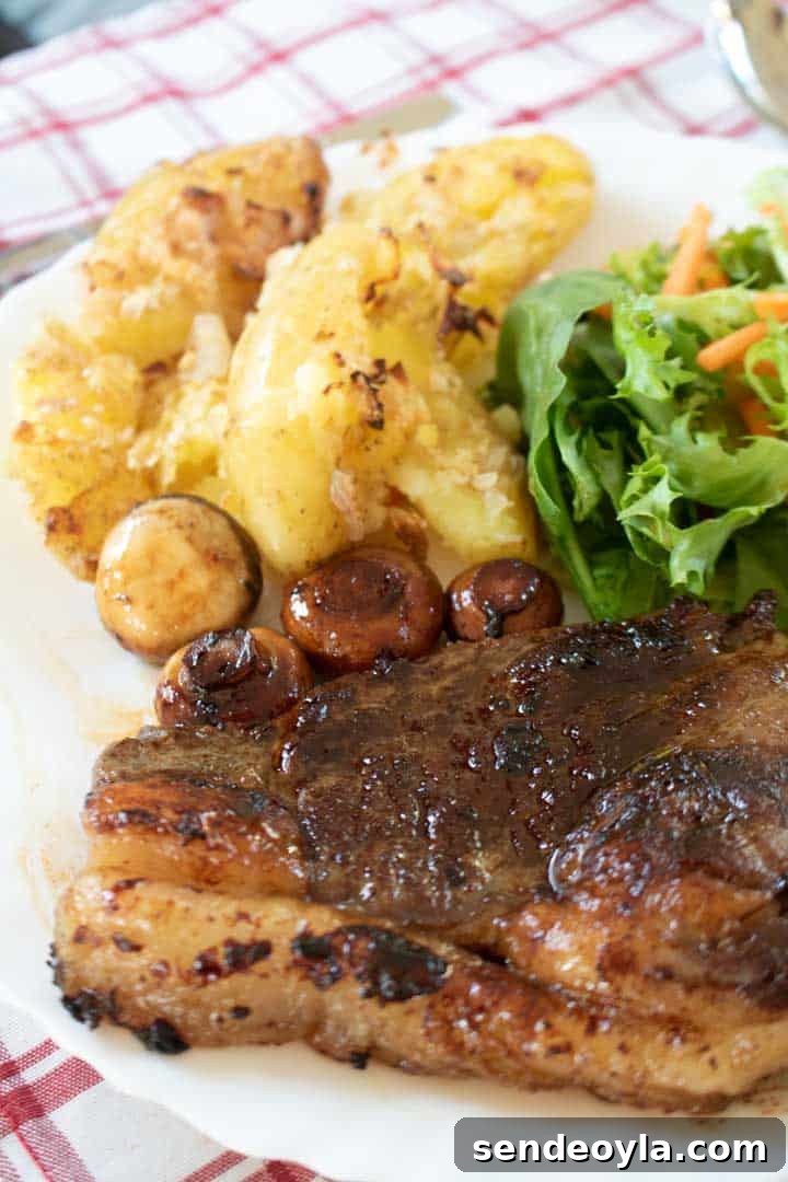 Side shot of crushed potatoes with sirloin steak, salad and mushrooms