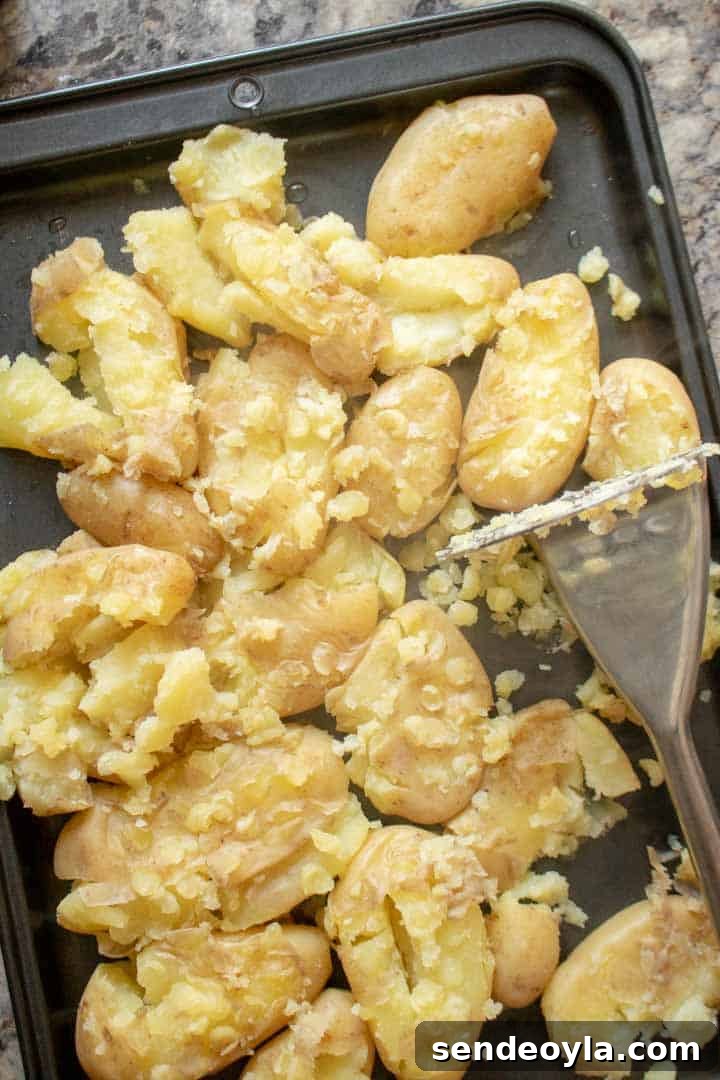 partially mashed new potatoes on a baking tray