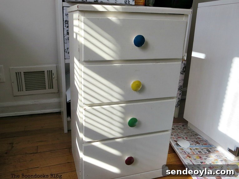 Before the nightstand makeover, the nightstand is yellowing and knobs are colorful.
