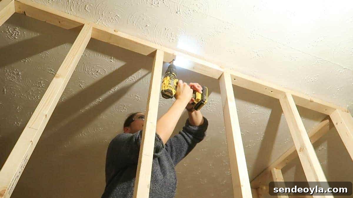 How to Build a Partition Wall: Step-by-Step DIY Guide 14 Screwing the partition wall from the top through to the ceiling