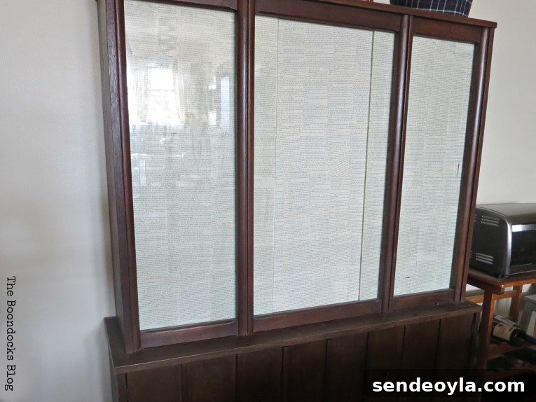 Decoupaged book pages onto glass doors of upper cabinet.