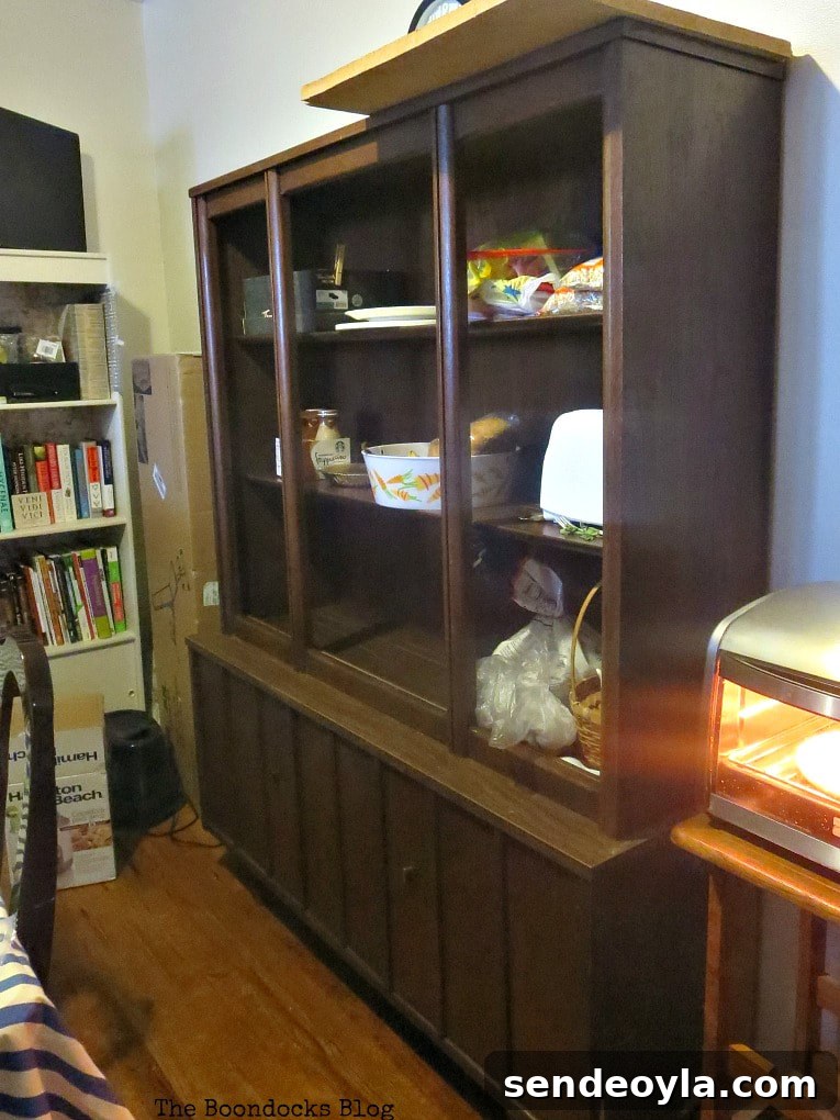 Showing the before picture of the China cabinet with glass doors and open shelves.