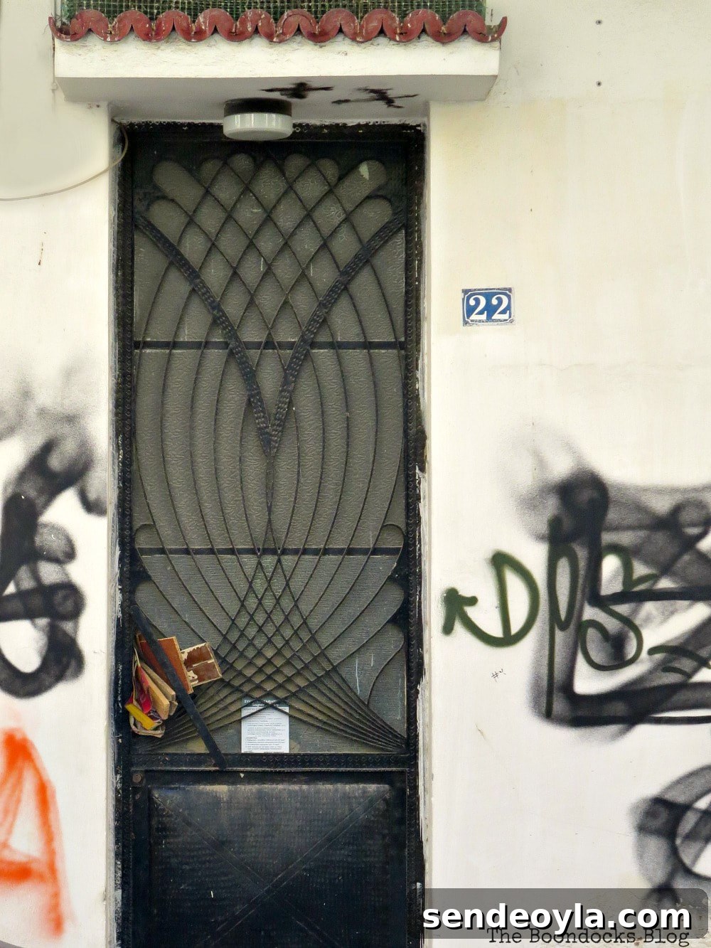 Black metal door with intertwining metal arches and graffiti