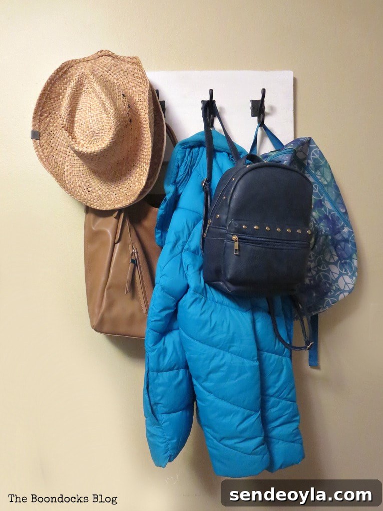 DIY Farmhouse Coat Rack for Your Entryway 14 Reality shot with lots of stuff on metal hooks, How to Make a Wooden Wall Hanger www.theboondocksblog.com