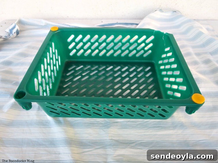 Upcycle Broken Plastic Baskets into Fabric Storage Bins 5 Placing the fabric under the green plastic basket.