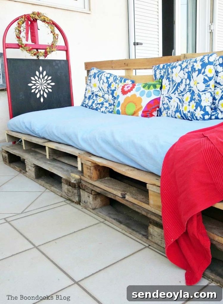 How to Build a DIY Pallet Sofa Without Tools 2 A completed DIY pallet couch covered with colorful cushions and blankets.