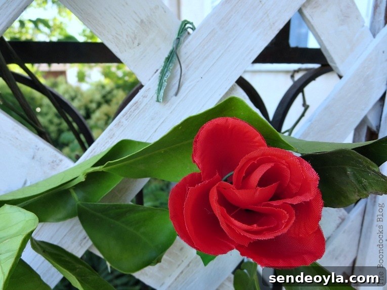 DIY Colorful Fence with Dollar Store Flowers 8 Placing the plastic stems as hooks on the lattice flower wall.