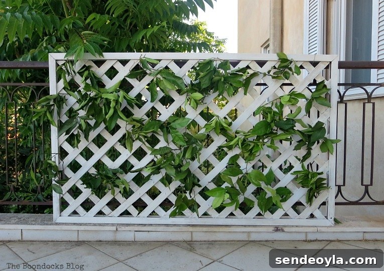DIY Colorful Fence with Dollar Store Flowers 6 Adding greenery to the lattice flower wall.