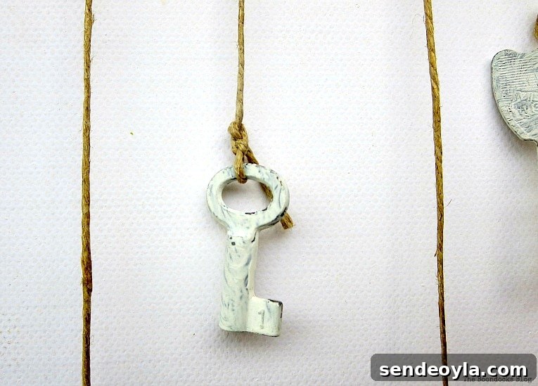 small key tied with thin twine, How to Make Simple Canvas Wall Art with Keys, www.theboondocksblog.com