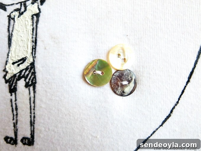 DIY T-Shirt Wall Art: Transform a Tee into Home Decor 8 Close up of three buttons sewn onto the white t-shirt.