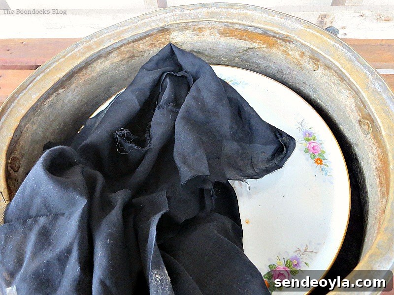 the cake stand placed inside the cauldron with a piece of fabric on top, A repurposed Antique Cauldron for Christmas theboondocksblog