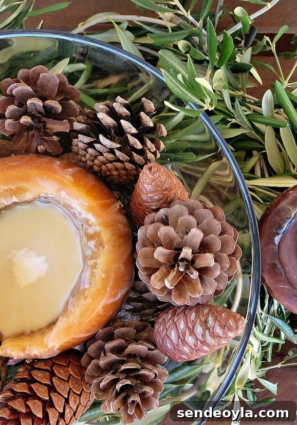 DIY Natural Thanksgiving Table Centerpiece Ideas 2 Centerpiece with Candle and pine cones in glass bowl surrounded by olive tree branches.