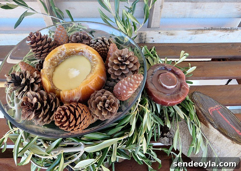 DIY Natural Thanksgiving Table Centerpiece Ideas 14 Glass bowl with another candle and pine cones, placed over olive branches, placed beside a candle and wood stump.