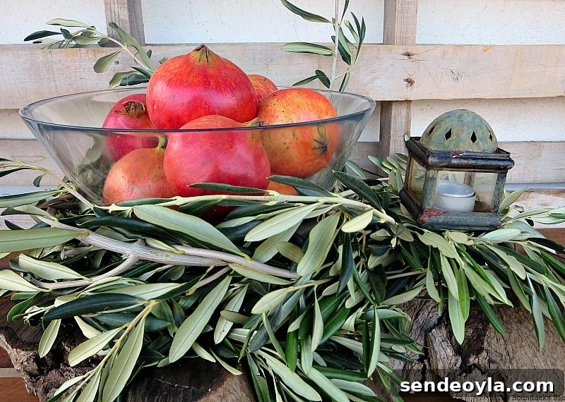 DIY Natural Thanksgiving Table Centerpiece Ideas 8 Glass bowl filled with pomegranates inside of olive branch circle and lantern to the side.
