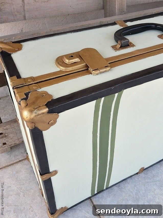 Transform a Vintage Suitcase into Chic Home Storage 18 Close up of green painted stripes, gold clasps and gold bumper on the vintage suitcase.