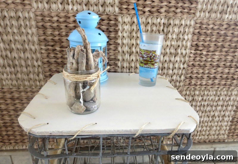 Milk Crate Table Upcycle: Stylish DIY Makeover 10 Close up of the white top of the table with a drinking cup, lantern and driftwood in a jar placed on top.