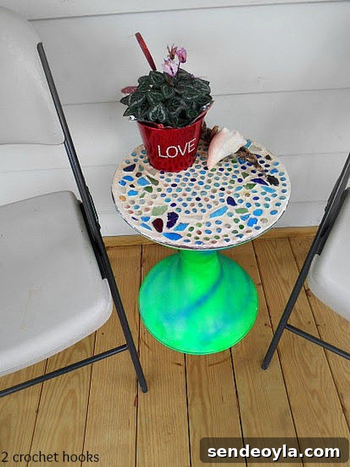 Sea glass mosaic table beside two folding chairs.