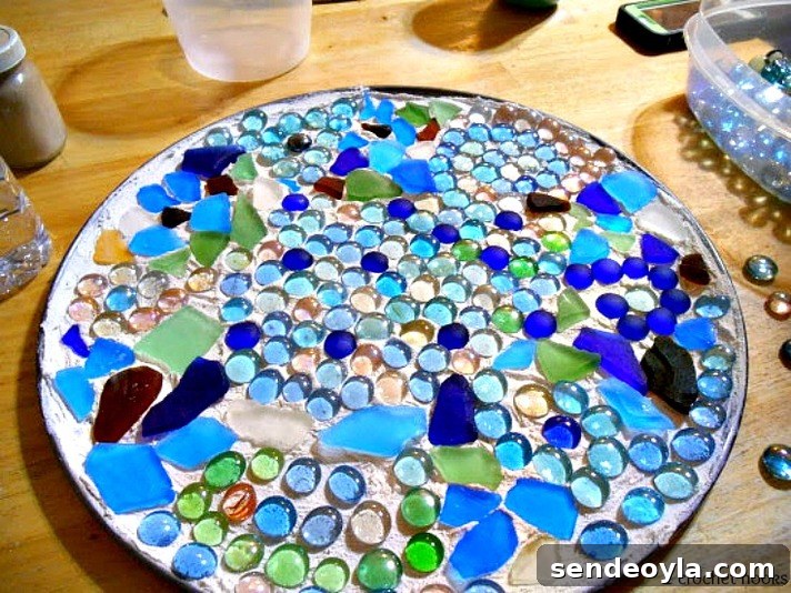 Pizza pan covered with grout and decorated with sea glass and marbles.