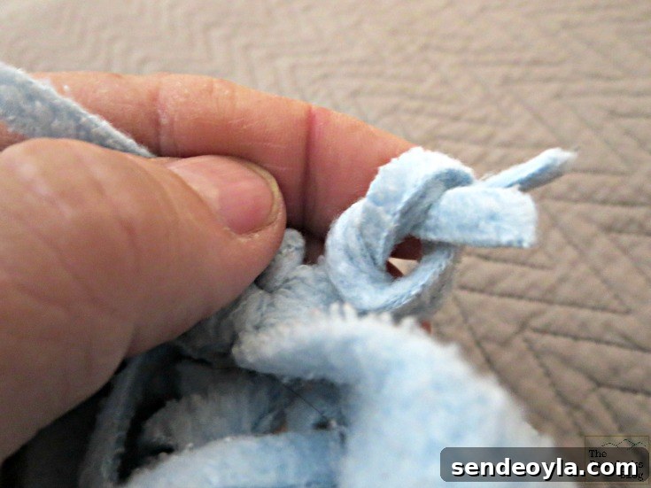 DIY Minimal-Sew Fleece Pillow 4 Tying the fringe to make the pillow edge